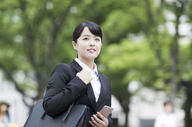 携帯を持っているスーツ姿の女性